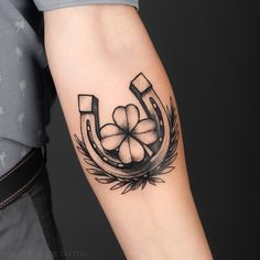 a man's arm with a clover and horseshoe tattoo on it