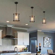 a kitchen with an island and three lights hanging from the ceiling over the stove top