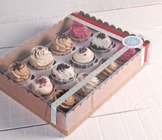 a box filled with lots of cupcakes on top of a white wooden floor