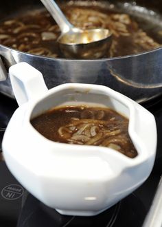 a white bowl filled with soup sitting on top of a stove next to a frying pan