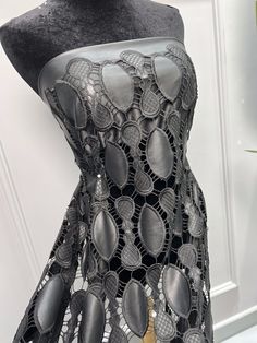 a mannequin with black lace and buttons on it's body, in front of a white door