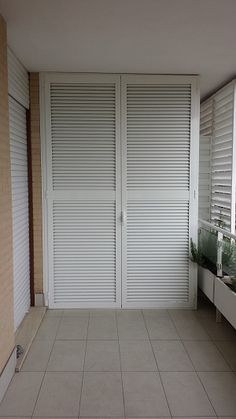 an empty room with white shutters on the doors and tiled flooring in front of it