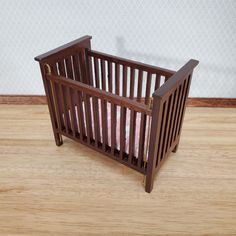 a small wooden crib sitting on top of a hard wood floor next to a wall