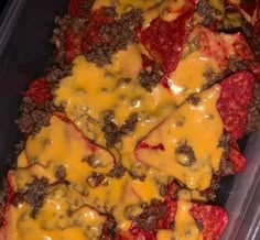 a plastic container filled with cheese and meat covered in sauces or other toppings