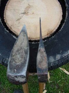 two old tools are sitting next to each other in front of a tire on the grass