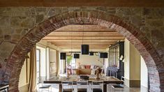 an archway leads to the living room and dining area in this modern home with stone walls