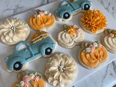 decorated cookies are arranged in the shape of cars and pumpkins on a marble surface