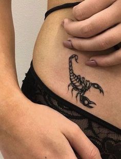 a woman is holding her stomach with a scorpion tattoo on it's side,