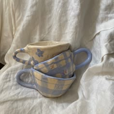 two blue and yellow cups sitting on top of a bed