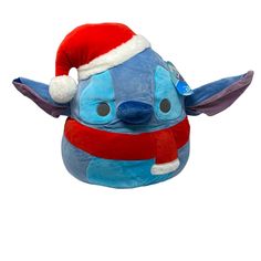 a blue stuffed animal with a santa hat on it's head and eyes, wearing a red scarf