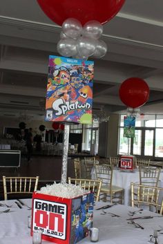 a table with some balloons on top of it and a video game sign in the middle