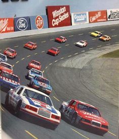 a group of cars driving around a race track in a book with an advertisement on it