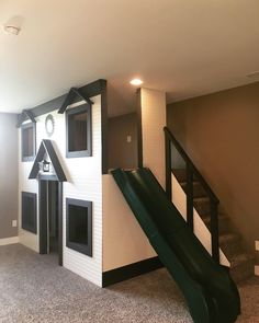 a play house with a slide in the middle and stairs leading up to the second floor