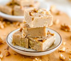 three pieces of cake sitting on top of a white plate next to another plate with walnuts