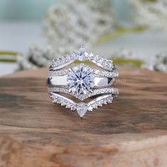 a diamond ring on top of a piece of wood with flowers in the back ground