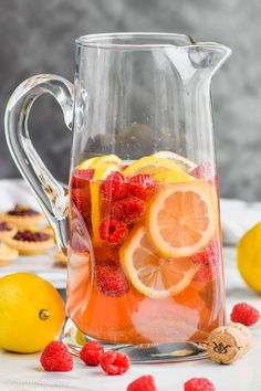 a pitcher filled with raspberries and lemons