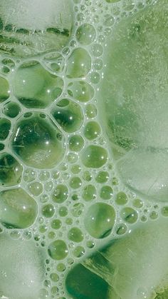 close up view of bubbles on the surface of green liquid with white and black dots