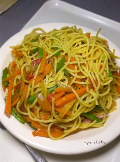 a white plate topped with spaghetti and vegetables