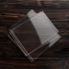 clear plastic sheets are stacked on top of each other in front of a wooden background