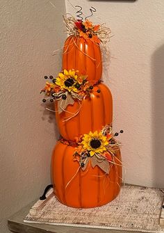 three tiered pumpkins decorated with sunflowers and leaves