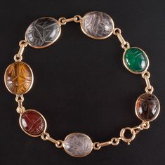 14k Yellow Gold Oval Cabochon Scarab Style Multi-Stone Bracelet 11.05gMetal Information: 14k Yellow GoldTotal Weight: 11.05gBracelet Width: 13mm - 3.5mmBracelet Length: 7.5"Stone InformationMain StoneGem Type: QuartzShape: Oval Cabochon (15.7mm x 11.75mm)Color: ClearClarity/Quality: ANumber of Stones: 1Accent StonesGem Type: QuartzShape: Oval Cabochon (13.2mm x 11.2mm / 11.8mm x 9.9mm)Color: Pink ClearClarity/Quality: ANumber of Stones: 2Accent StonesGem Type: AgateShape: Oval Cabochon (11.5mm x 9.4mm)Color: RedClarity/Quality: ANumber of Stones: 1Accent StonesGem Type: AgateShape: Oval Cabochon (11.5mm x 9.8mm)Color: Orange RedClarity/Quality: ANumber of Stones: 1Accent StonesGem Type: Tigers EyeShape: Oval Cabochon (13.7mm x 11.4mm)Color: BrownClarity/Quality: ANumber of Stones: 1Accent Luxury Oval Cabochons With Center Stone, Luxury Platinum Oval Cabochon Jewelry, Luxury Oval Cabochon Brooch Jewelry, Luxury Gold Oval Cabochons, Luxury Amber Beads Gems And Cabochons, Luxury Handmade Vintage Beads, Gems And Cabochons, Luxury Engraved Oval Cabochon Jewelry, Deep Autumn Palette, Rose Gold Accessories