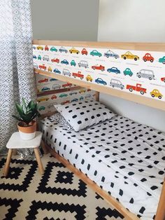 a child's bed with cars on the wall next to a potted plant