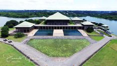 an aerial view of a large building next to a body of water with trees in the background