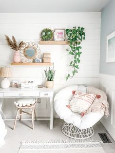 a white desk and chair in a small room with plants on the shelves above it