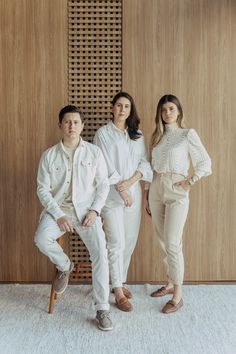 three people are posing for a photo in front of a wall with wood paneling