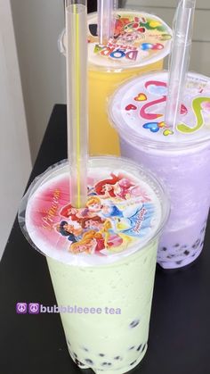 three bubble teas are lined up on a table