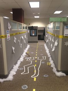 an office hallway decorated with yellow caution tape and fake white clouds on the floor in front of cubicles