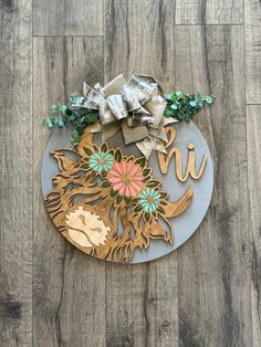 a metal sign with flowers and leaves on it sitting on a wooden floor next to a wall