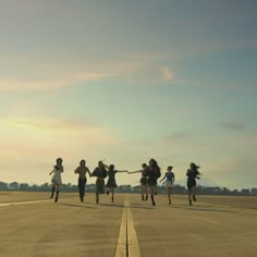 a group of people running across an airport tarmac with their arms in the air