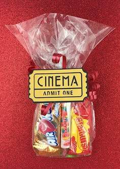 a bag filled with candy sitting on top of a red table next to a sign that says cinema admit one