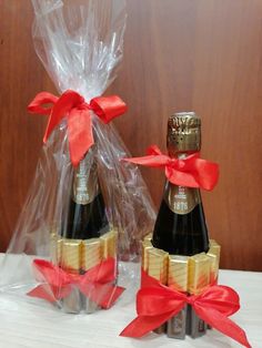 two bottles of champagne wrapped in plastic and tied with red ribbon, sitting next to each other