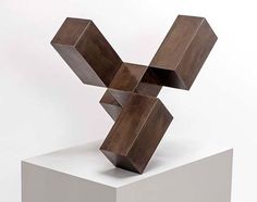 a wooden sculpture sitting on top of a white pedestal