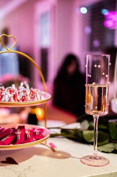 two tiered trays filled with candy and wine glasses sitting on a white table