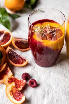 a glass filled with liquid next to sliced oranges