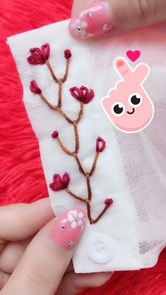 a person with pink nail polish holding up a small piece of paper that has flowers on it