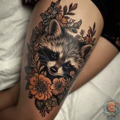 a raccoon with flowers and leaves on it's thigh is seen in this tattoo