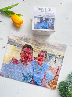 two men are sitting on a puzzle piece next to tulips and a box