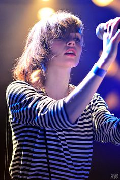 a woman in striped shirt holding a microphone