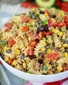 a white bowl filled with pasta salad on top of a checkered table cloth