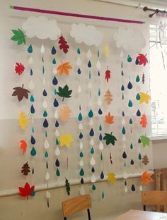 a classroom with paper raindrops hanging from the ceiling and wooden chairs in front of it