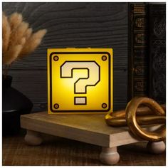 a yellow question sign sitting on top of a wooden table next to a black vase