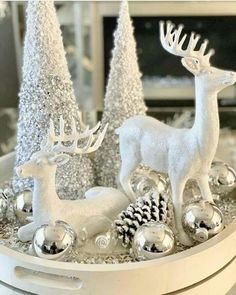 silver and white christmas decorations in a bowl with deer figurines on the side