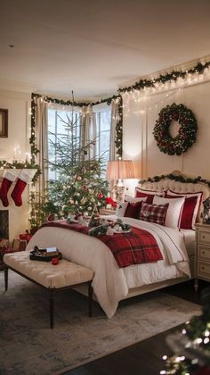 a bedroom decorated for christmas with red and white bedding, stockings, wreaths and lights on the windowsill