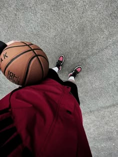 a person standing next to a basketball on top of a cement ground with their feet in the air