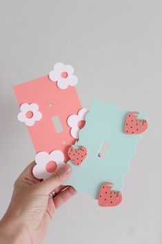 someone is holding up some pink and blue paper with hearts on it in front of a white wall