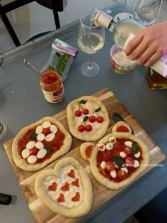 four homemade pizzas with toppings are on a cutting board and ready to be served